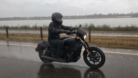 Motorcycle rider on a cruiser riding on a wet rainy highway