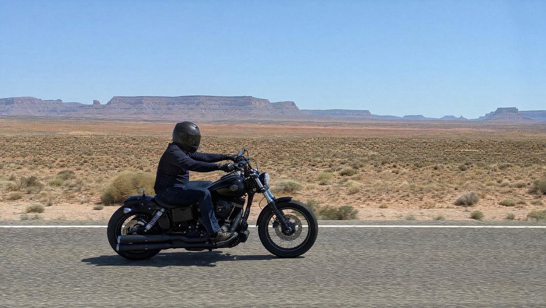 Motorcycle rider on a cruiser riding an open desert highway in the American Southwest in hot weather