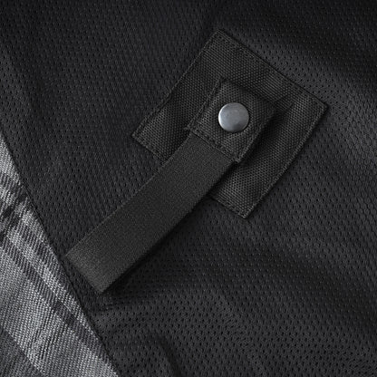 Close-up of a black mesh fabric surface with a black strap and metal snap fastener, plus a small portion of a gray plaid pattern at the lower left.