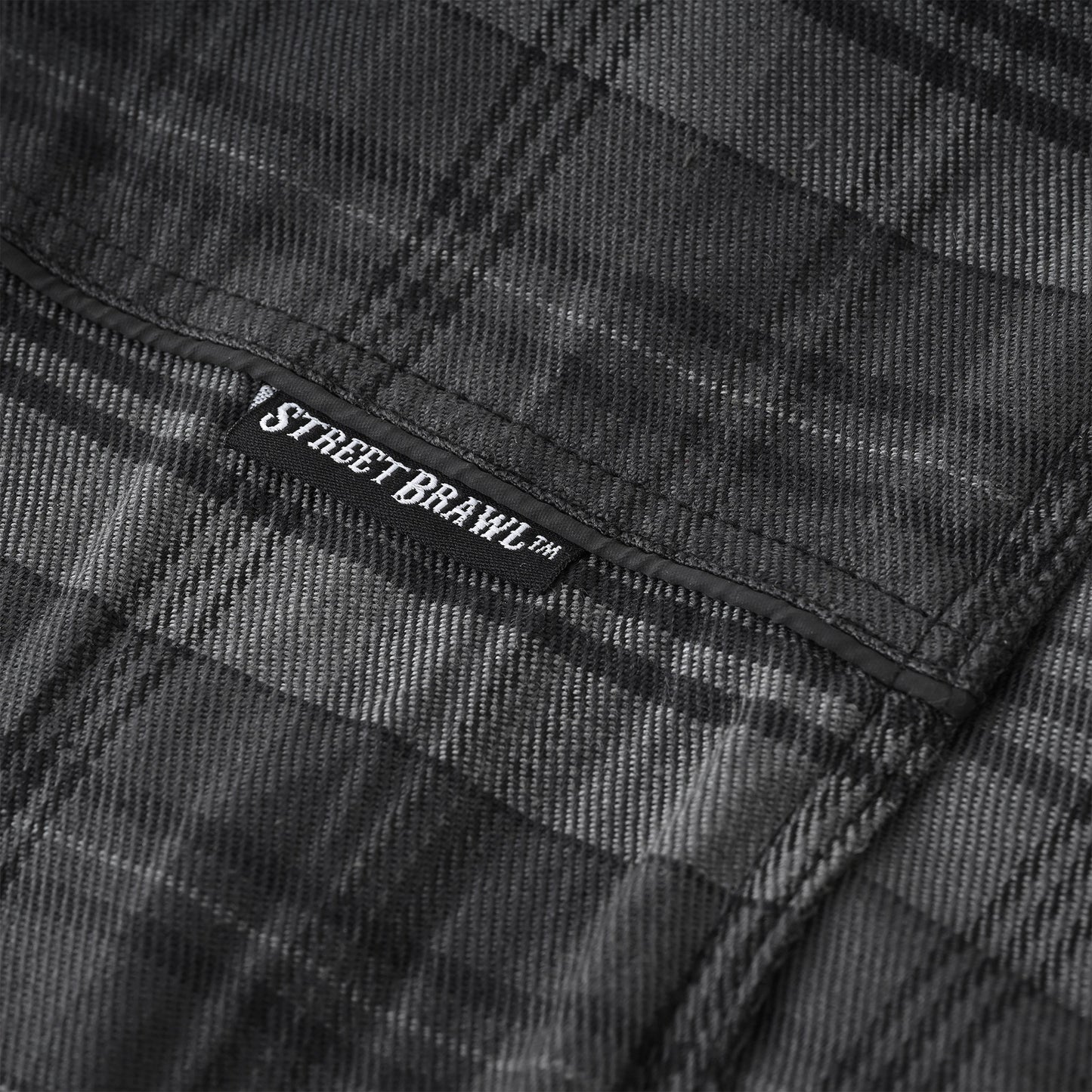 Close-up of a dark gray and black plaid fabric with a visible black label reading STREET BRAWL™.