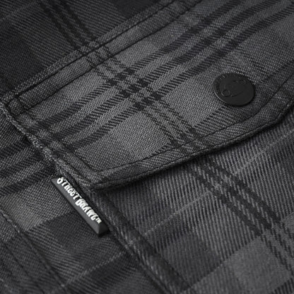 Close-up of a dark gray and black plaid flannel shirt fabric, showing a buttoned pocket with a black brand tab that reads Street Style.
