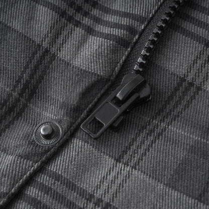 Close-up of a black zipper pull and button detail on a dark gray and black plaid fabric jacket.