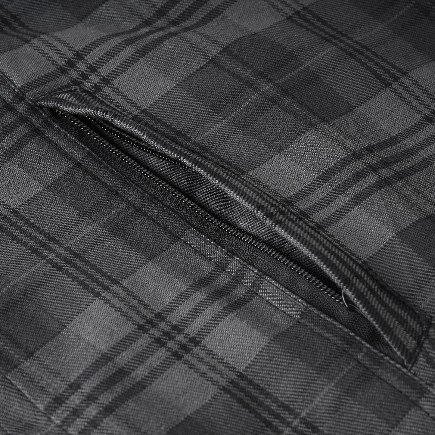 Close-up of a dark gray and black plaid fabric with a diagonal zippered pocket.