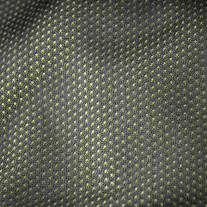 A close-up of a woven fabric with a repeating small geometric dot pattern in muted yellow-green on a dark charcoal gray background.