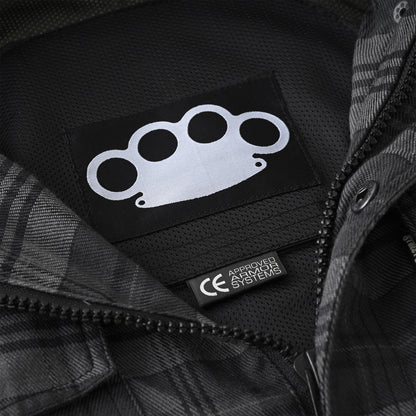 Close-up of a black zippered jacket interior showing a black patch with a white brass-knuckle style logo and a small black tag reading 'APRON HAZMAT SYSTEMS'.