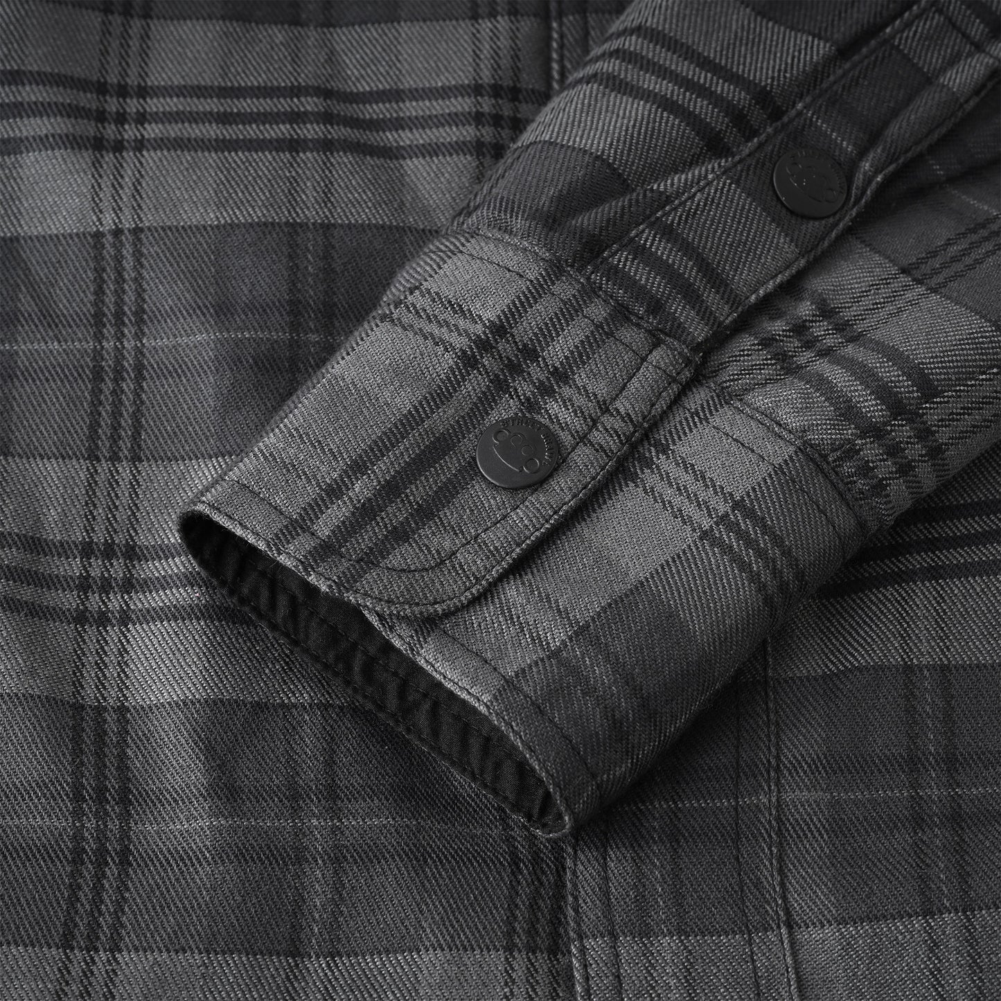 Close-up of a dark gray and black plaid button-down shirt showing the fabric texture and cuff detail.